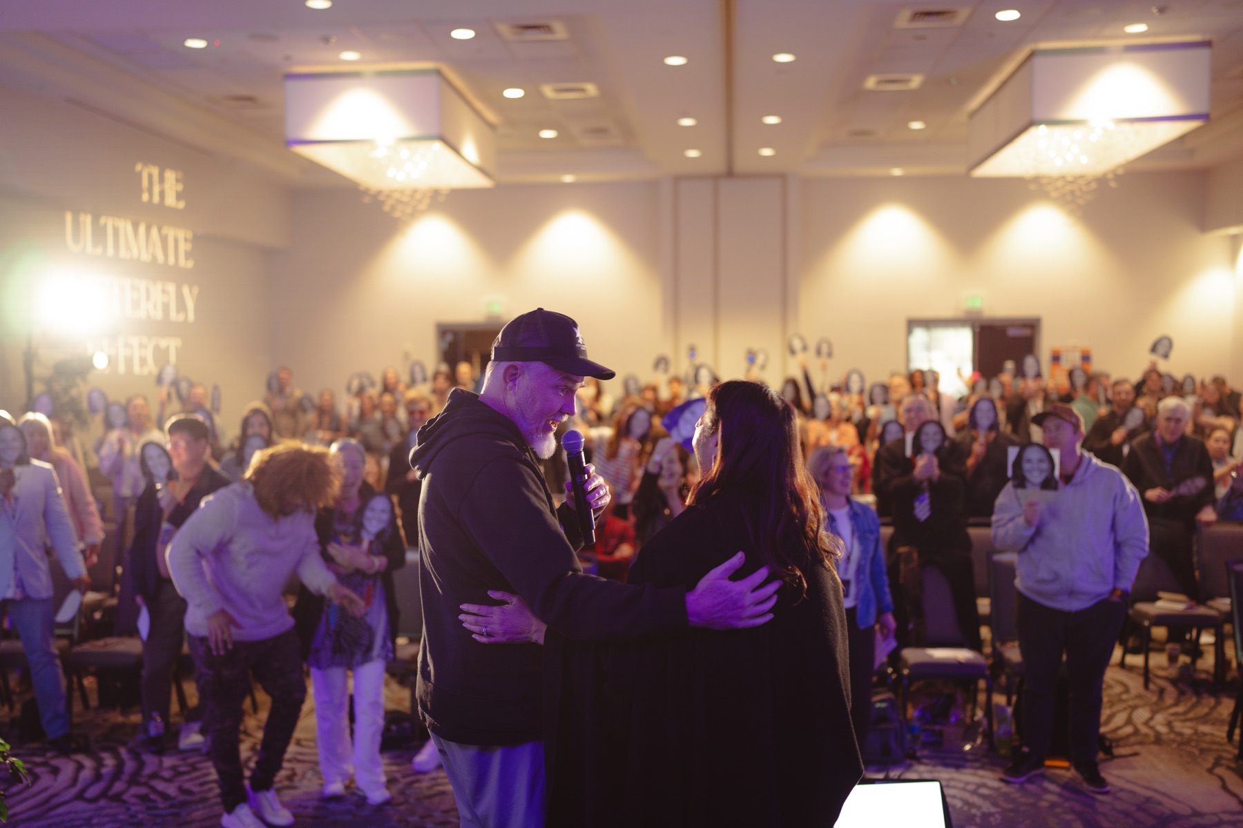 Judy Thureson on stage with an audience holding photographs