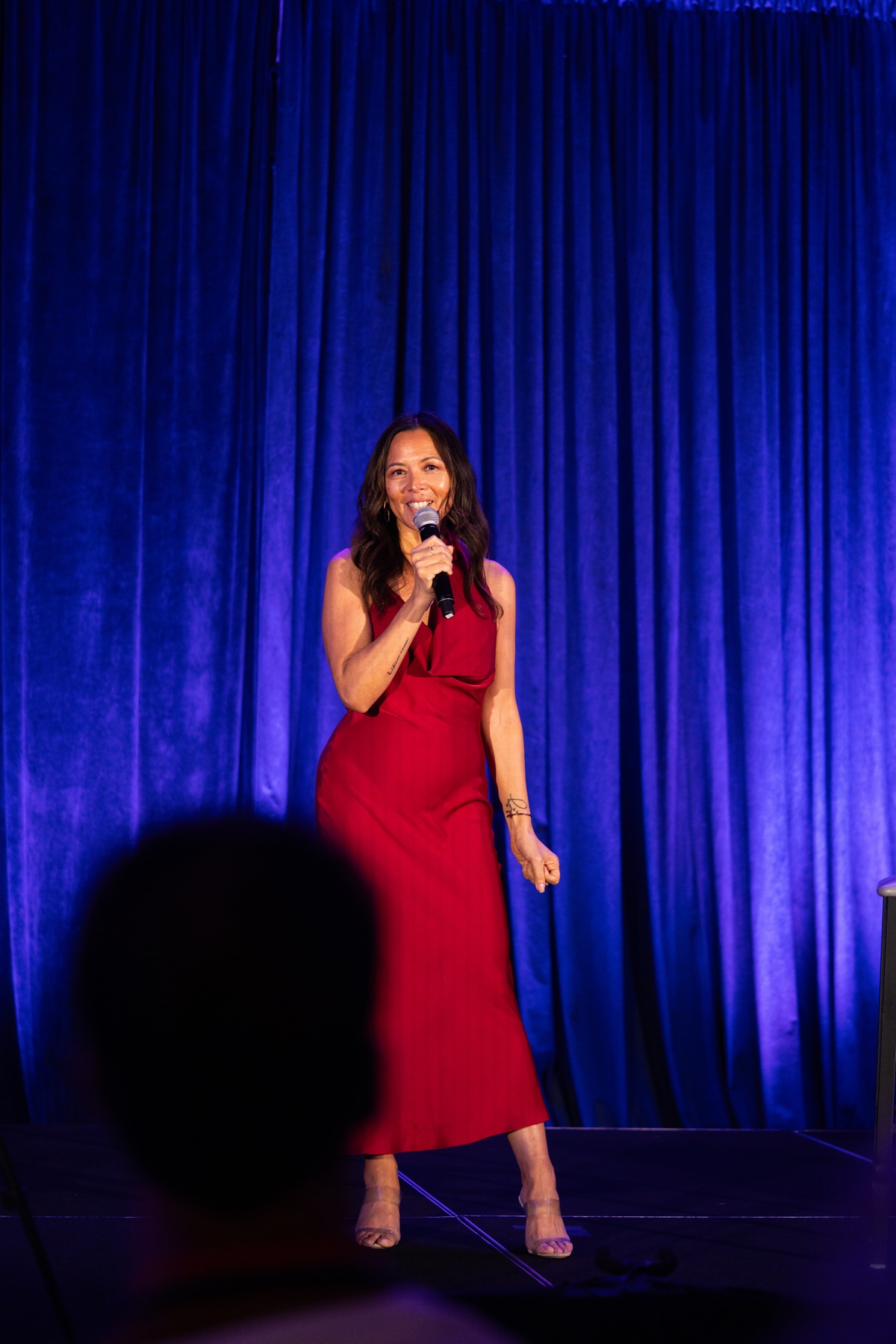 Judy Thureson speaking on stage in a red dress